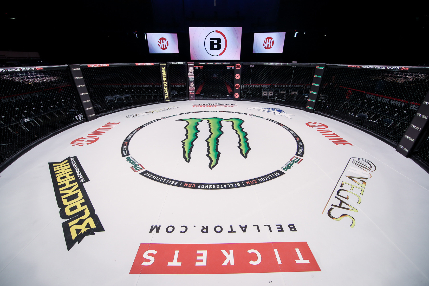 Cage Bellator 286 vide vue en plongée avec tapis couvert de logos sponsors : Monster Energy au centre, Showtime, Blackhawk, Visit Las Vegas, Bellator.com, DragonPay — illustration de l'économie du sponsoring dans les grandes organisations MMA