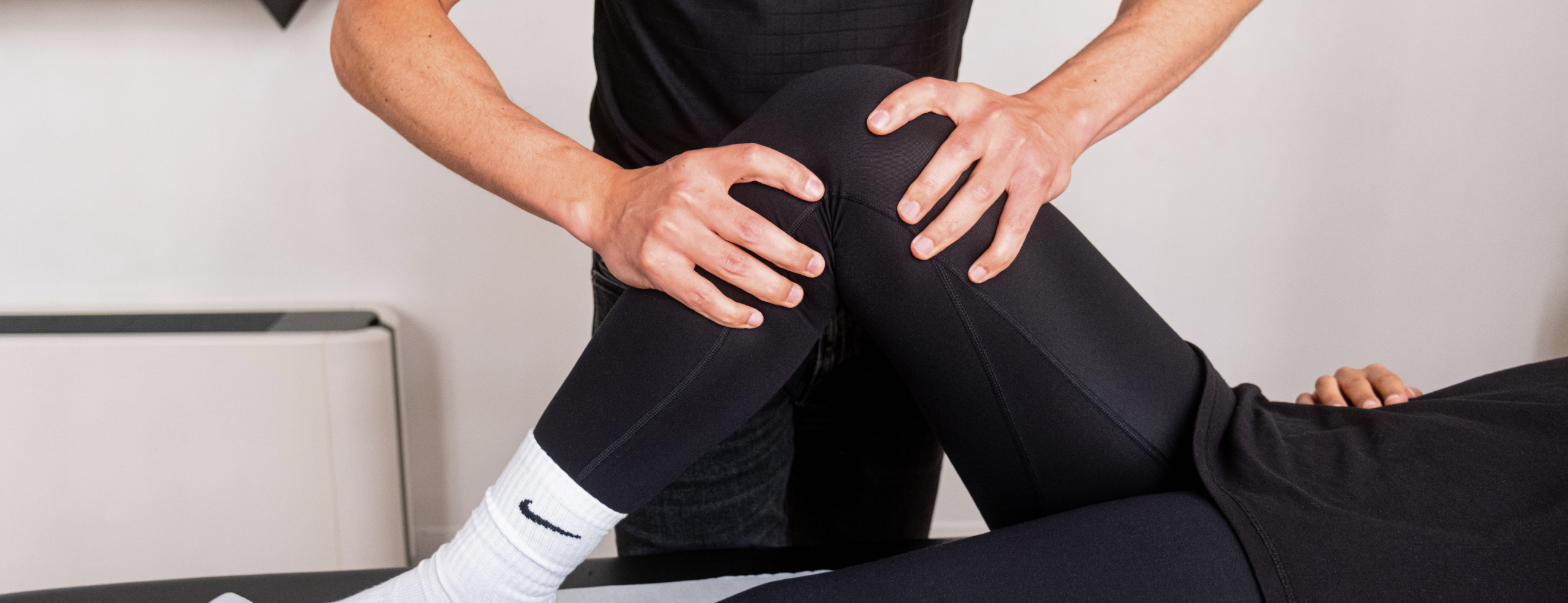 Kinésithérapeute mobilisant la hanche d'un athlète de sports de combat